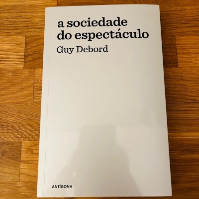Livro branco 'a sociedade do espectáculo' de Guy Debord sobre mesa de madeira