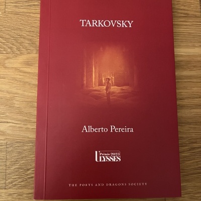 Livro vermelha com título Tarkovsky e autor Alberto Pereira sobre mesa de madeira