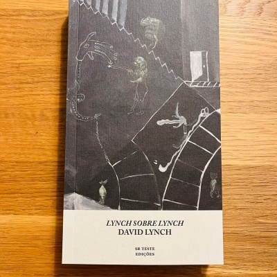 Livro 'Lynch Sobre Lynch' de capa preta e branca com ilustrações sobre uma mesa de madeira clara