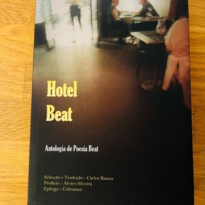 Capa de livro 'Hotel Beat Antologia de Poesia Beat' com imagem desfocada de pessoas em mesas