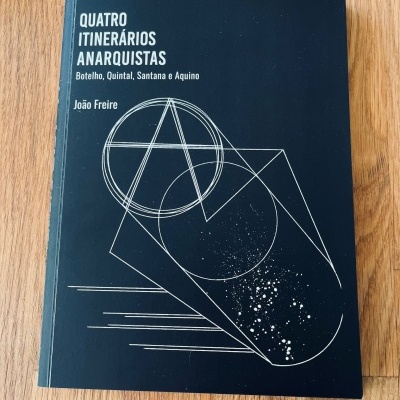 Livro com capa preta e título branco sobre madeira