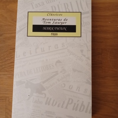 Capa do livro 'Aventuras de Tom Sawyer' de Mark Twain com fundo branco e design de recortes de jornais