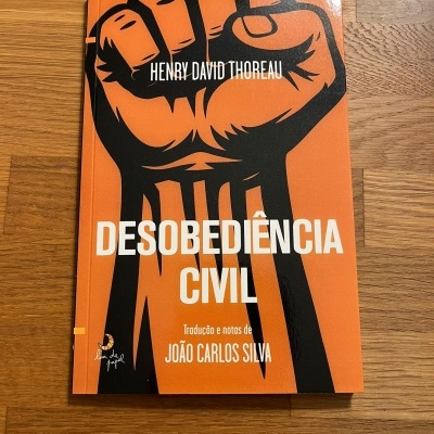 Capa do livro Desobediência Civil com punho cerrado em fundo laranja