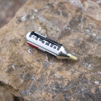 Cartucho de gás CO2 metálico preto e branco sobre rocha