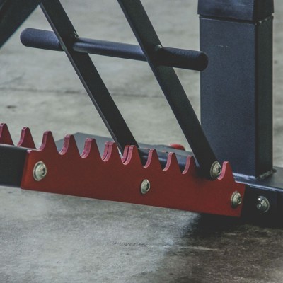 Estrutura metálica preta e vermelha com dentes recortados sobre piso cinzento