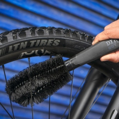 Escova de limpeza preta a limpar roda de bicicleta com pneu preto e texto LTN TIRES, fundo azul