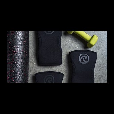 Equipamento de fitness: tapete preto com salpicos vermelhos, haltere amarelo, suportes pretos para pulso com logótipo.