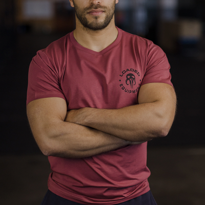 T-shirt vermelha com logotipo preto no peito usada por pessoa de braços cruzados