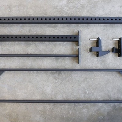 Peças metálicas pretas para montagem, dispostas no chão de cimento.