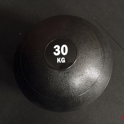 bola medicinal preta com peso 30 KG sobre chão escuro