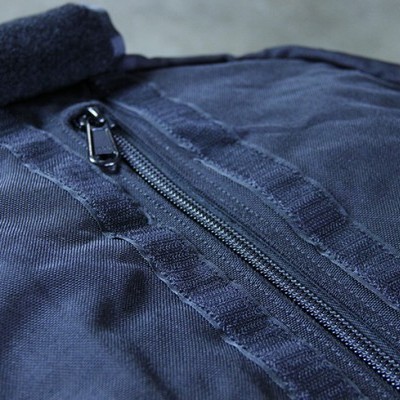 Mala azul escuro com fecho de correr preto sobre superfície cinzenta