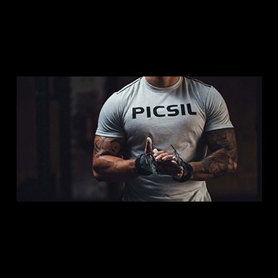 Homem musculado a usar camiseta cinza com texto PICSIL e luvas de treino pretas.