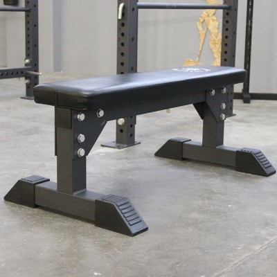 Banco de musculação preto com assento acolchoado, em ginásio com chão cinzento