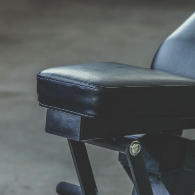 Assento preto de equipamento de ginásio com estofado em couro sintético e estrutura metálica.