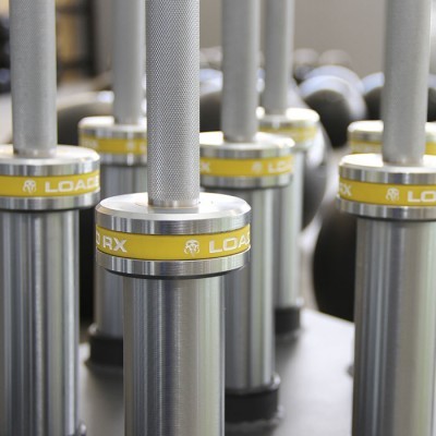 Barras de pesos metálicos para ginásio com inscrição 'LOAD RX' em amarelo e branco