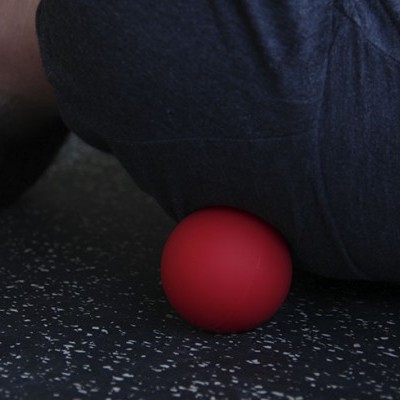 Bola vermelha para massagem sob as costas de uma pessoa