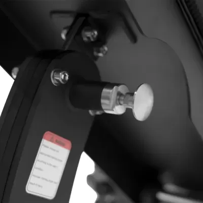 Estrutura metálica preta com parafusos e botão cromado próximo a etiqueta com texto