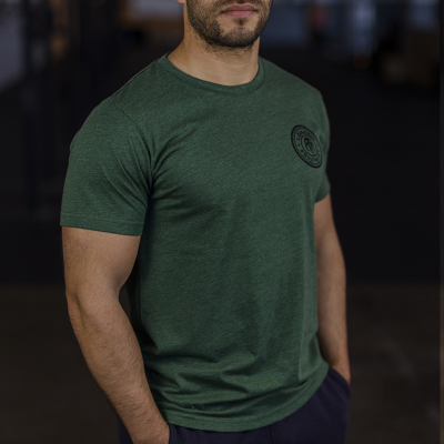 Homem com t-shirt verde escura com estampa preta circular no peito