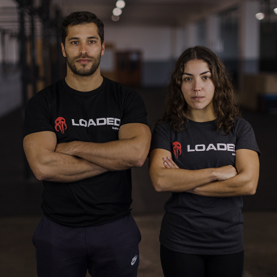 Homem e mulher com t-shirts pretas e cinza com logotipo 'LOADED', em ginásio