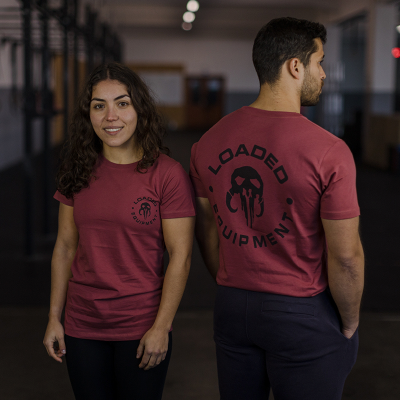 Dois modelos com t-shirts vinho com logotipos pretos num ginásio.