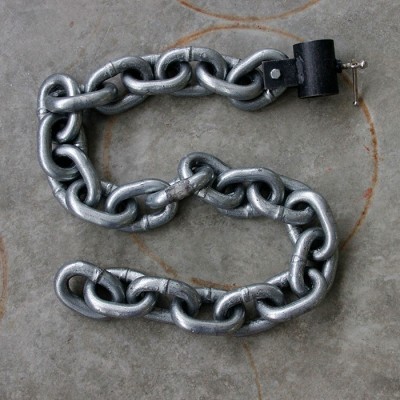 Corrente de metal prateado com cadeado preto sobre chão cinzento