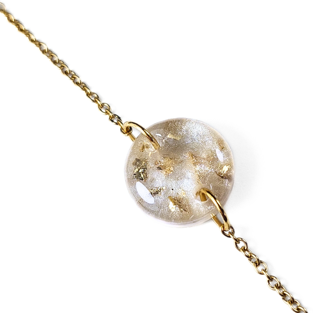 Pulseira dourada com pendente redondo transparente com flocos dourados