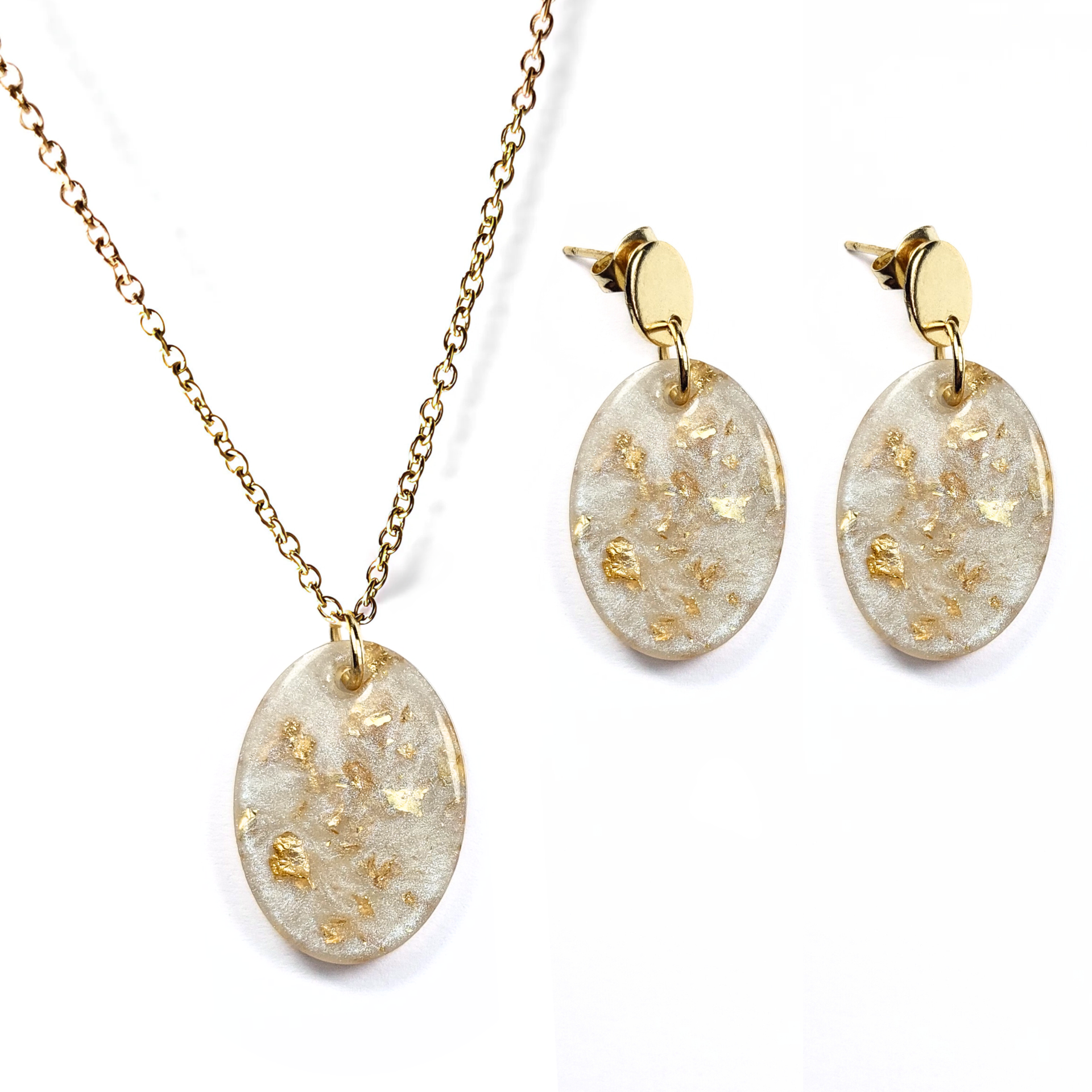 Conjunto de joias com colar e brincos com pendentes ovais transparentes e detalhes dourados.