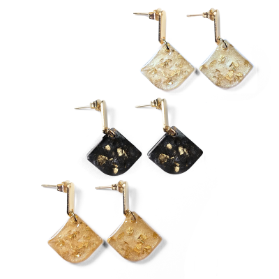Três pares de brincos quadrados tombados em resina com folhas douradas, em tons claros, preto e dourado, com fecho dourado.