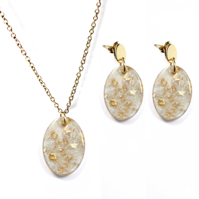 Conjunto de joias com colar e brincos com pendentes ovais transparentes e detalhes dourados.