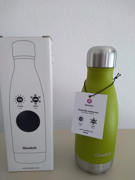 Garrafa isotérmica verde Qwetch com tampa prateada ao lado da caixa branca