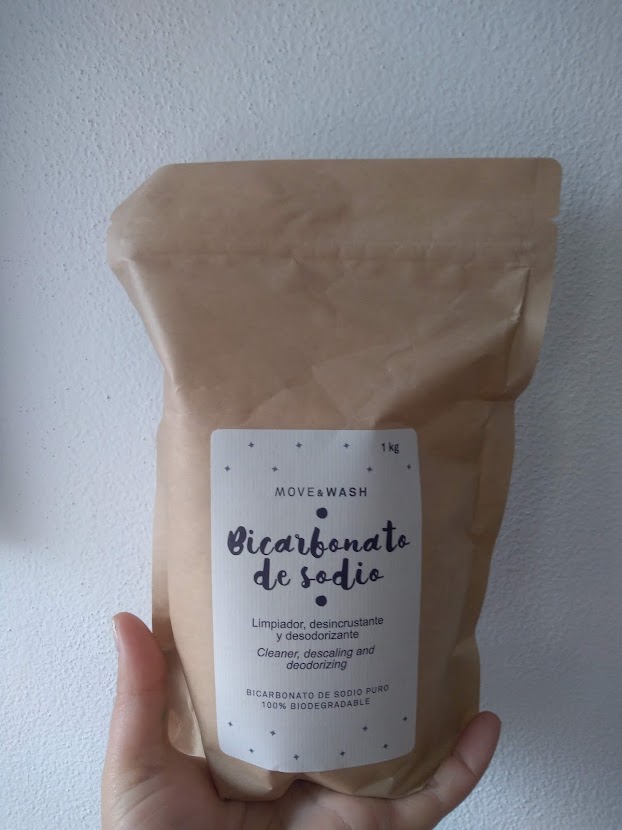 Pacote castanho de bicarbonato de sódio biodegradável com rótulo branco na mão