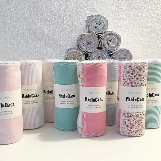 Toalhas multifunções coloridas e estampadas com etiquetas MadInCasa, empilhadas e enroladas