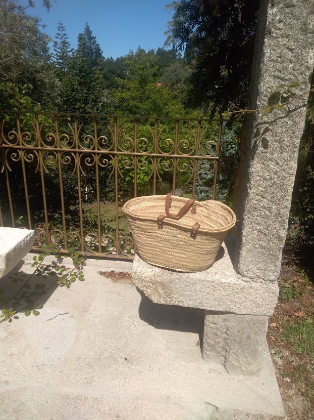 Cesta de palha com alças de couro num banco de pedra ao ar livre