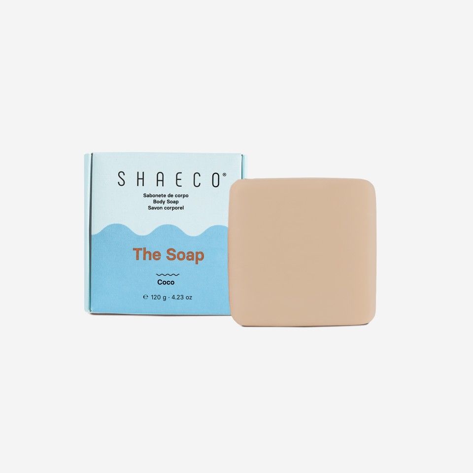 Sabonete cuadrado beige junto a caja azul claro y blanca con texto de marca SHAECÓ y descripción del producto.