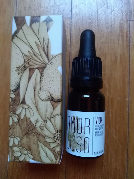 Frasco com conta-gotas e caixa com ilustração botânica sobre madeira