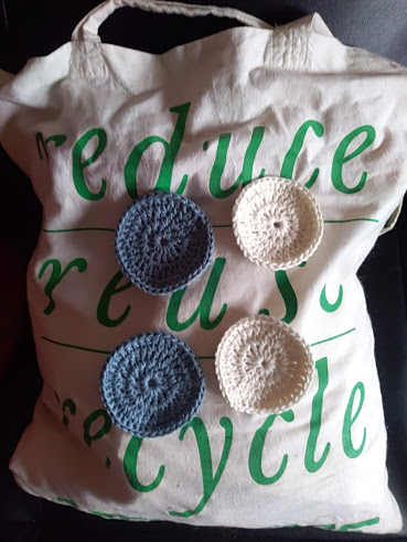 Saco de tecido branco com texto verde e discos de crochê azul e branco