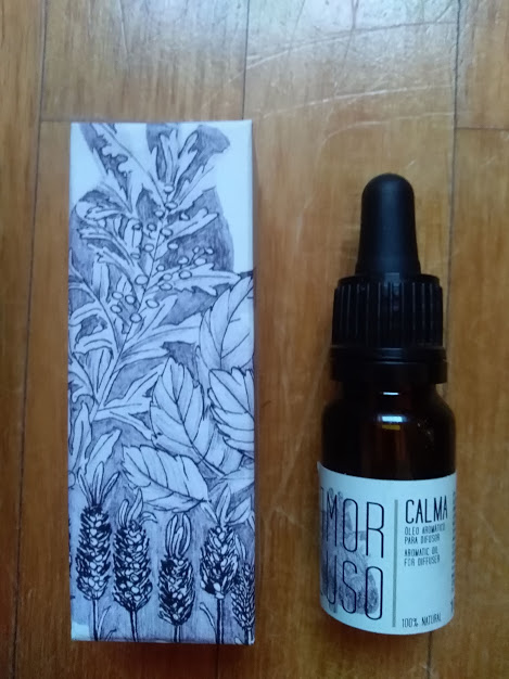 Frasco de vidro castanho com conta-gotas e caixa com ilustração botânica sobre madeira