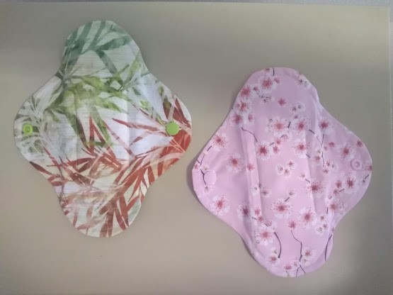 Dois pensos reutilizáveis de tecido com padrões florais sobre superfície clara