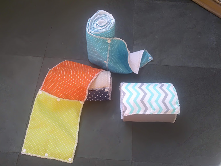 Três mantas de retalhos e padrões variados sobre chão escuro.