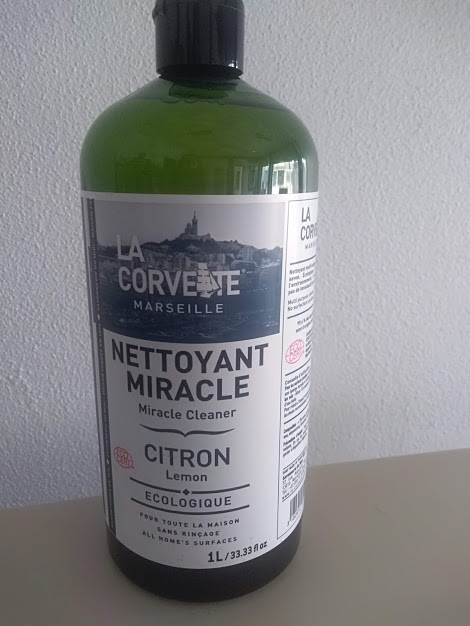 Frasco verde de produto de limpeza com rótulo branco e texto em francês e inglês