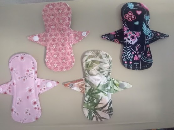 Quatro pensos reutilizáveis coloridos com diferentes padrões florais e decorativos