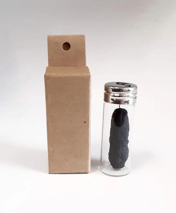 frasco de vidro com objeto preto e caixa de cartão castanha