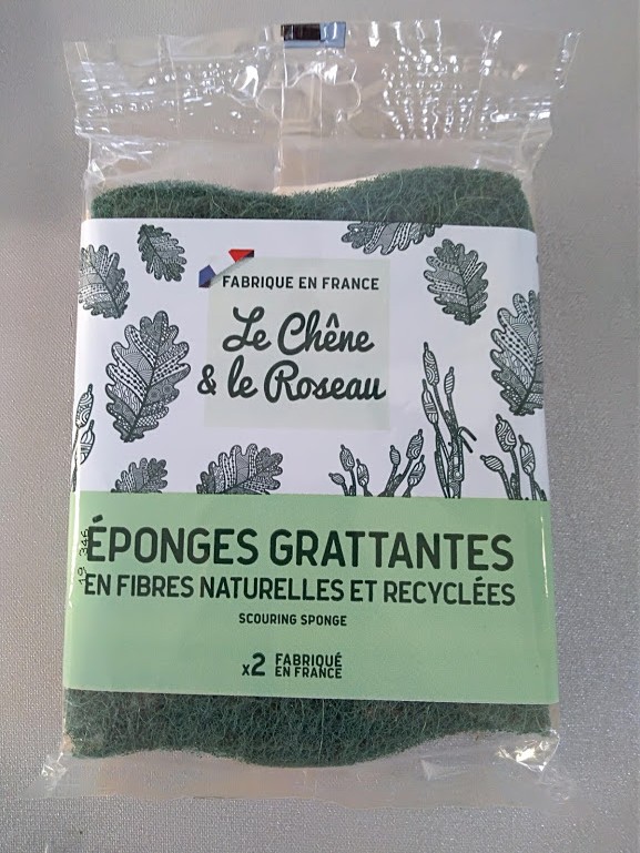 Esponjas verdes abrasivas em embalagem transparente com rótulo branco e verde e desenhos de folhas.