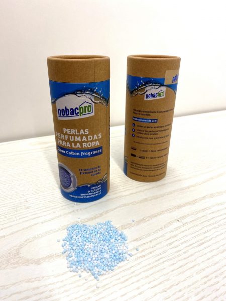 Frascos cilíndricos nobacpro com pérolas perfumadas para roupa e pérolas azuis e brancas sobre mesa de madeira.