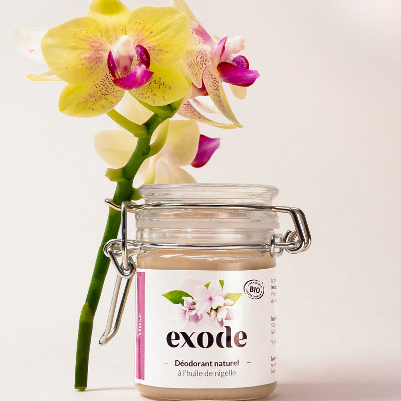 Frasco de desodorizante natural Exode com flor amarela e rosa