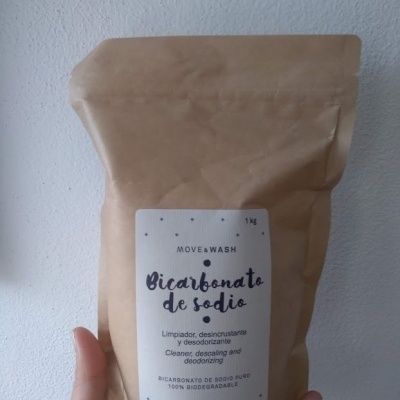 Pacote castanho de bicarbonato de sódio biodegradável com rótulo branco na mão