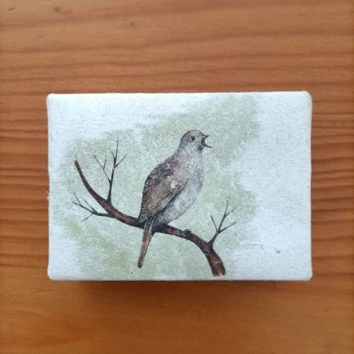 Caixa retangular em madeira pintada de branco com ilustração de pássaro num ramo