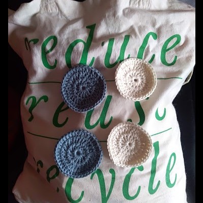 Saco de tecido branco com texto verde e discos de crochê azul e branco