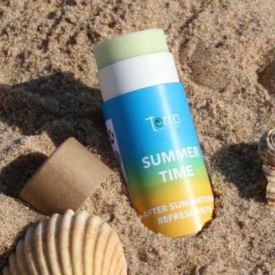 Stick após sol com embalagem azul e amarela na areia junto a conchas