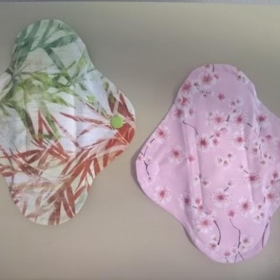 Dois pensos reutilizáveis de tecido com padrões florais sobre superfície clara